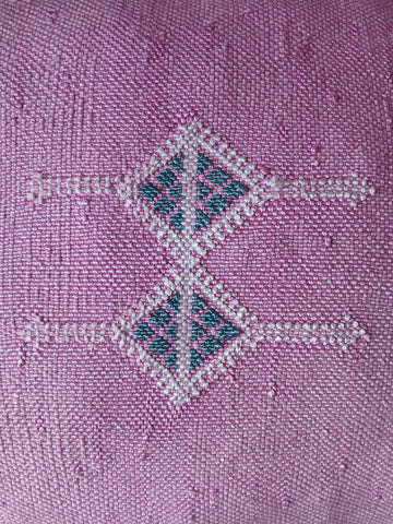 Pair of beaded earrings on a textured purple fabric background