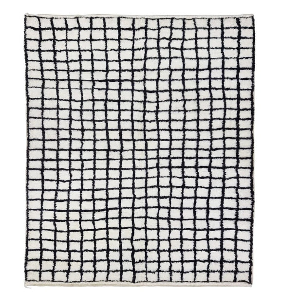 A rectangular area rug with a black hand-drawn grid pattern on an off-white background, shown flat against a solid white backdrop.