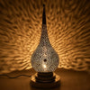 Decorative lamp with intricate design casting shadows on a textured wall.