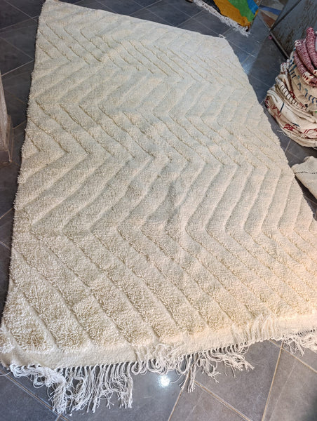 Handwoven Moroccan ivory wool rug — chevron pattern in relief, workshop view