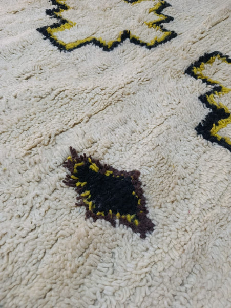 Close-up of cross medallions in black and yellow on ivory Azilal rug