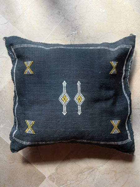 Decorative pillow with geometric patterns on a black 
textured surface