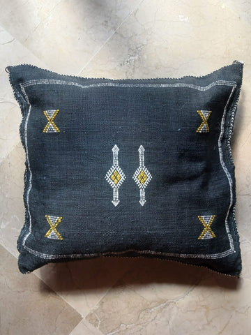 Decorative pillow with geometric patterns on a black 
textured surface