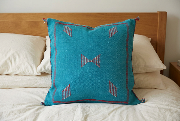 Mizan turquoise pillow on ivory bedding