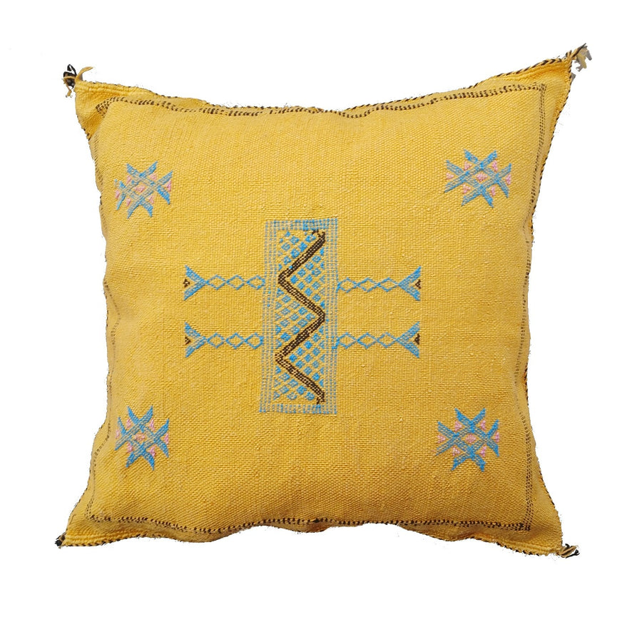Yellow pillow with blue and brown embroidery on a white background