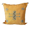 Yellow pillow with blue and brown geometric patterns on a white background