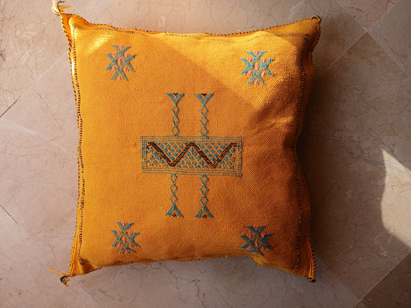 Yellow pillow with decorative patterns on a textured surface